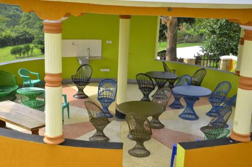 a patio with tables and chairs and a green wall at Karobwa Summit View in Fort Portal