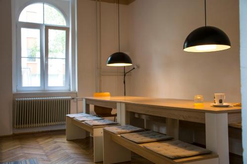 um quarto com uma mesa e duas luzes e bancos em Hostel DIC em Ljubljana
