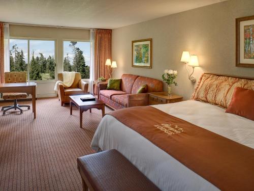 ポート・エンジェルスにあるOlympic Lodge by Ayresの大きなベッドとデスクが備わるホテルルームです。