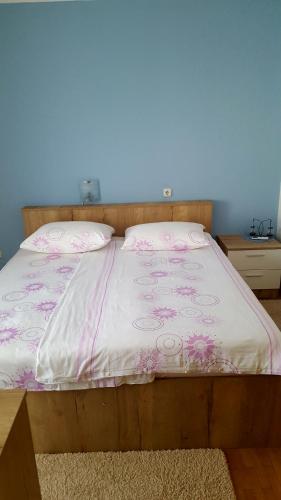 Una cama con un edredón rosa y blanco. en Guesthouse Matušan's place en Rab