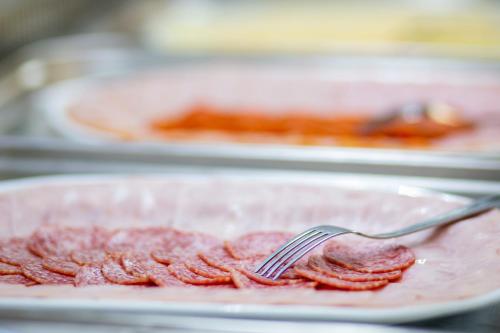 a fork sitting on a plate of meat with bacon at Hotel Carpe Diem in Siófok