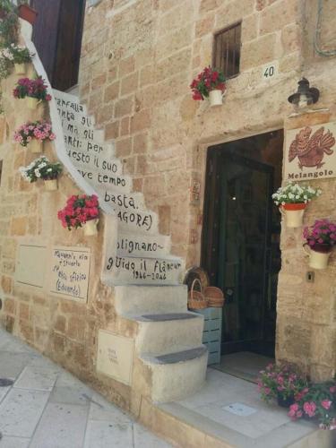 a stone building with stairs and signs on it at B&B Casa Dorsi in Polignano a Mare