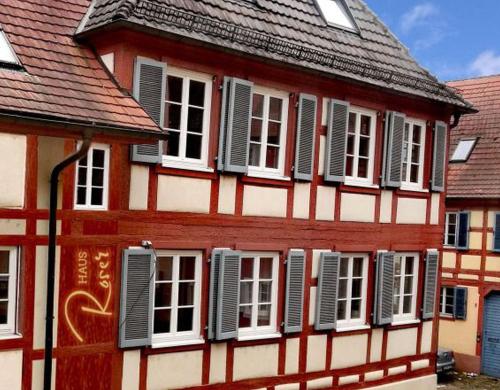 ROSER Suiten في غينغنباخ: مبنى احمر و ابيض بنوافذ و مصاريع بيضاء