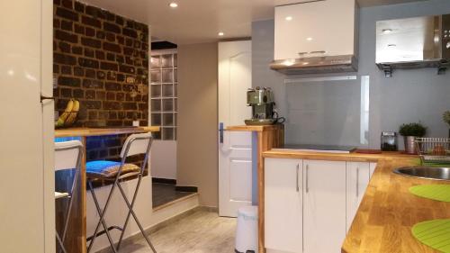 a kitchen with white cabinets and a brick wall at DOUX COCON DE 50 m2 PARIS-LE RAINCY in Le Raincy