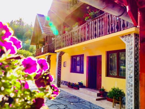 a yellow house with a balcony and flowers at Casa Ursu in Cîrţişoara