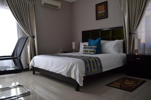 a bedroom with a large bed with blue pillows at Triple Palms Bed and Breakfast in Gaborone
