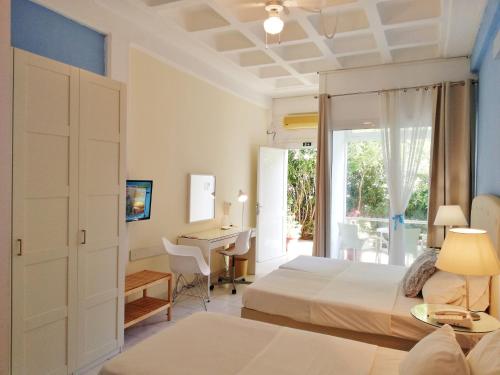 a hotel room with two beds and a desk at Homely Studios in Chios
