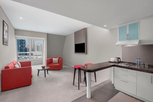 a kitchen and living room with a table and red chairs at Leva Hotel and Suites, Opposite Downtown in Dubai