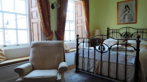 a bedroom with a bed and a chair and windows at The Georgian House in Watchet