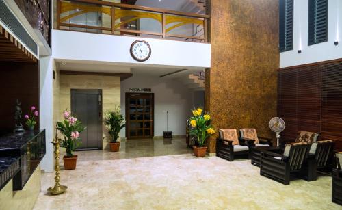 un vestíbulo con sillas y un reloj en la pared en Hotel Mary Land Velankanni en Velānganni