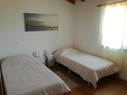 2 Betten in einem kleinen Zimmer mit Fenster in der Unterkunft Casa Pompona 3 in Rogil