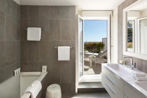 bagno con vasca, lavandino e finestra di Hôtel Barrière Le Royal La Baule a La Baule