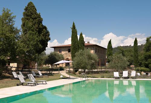 ein Pool mit Stühlen und ein Haus im Hintergrund in der Unterkunft Borgo Mulignone in Casole dʼElsa