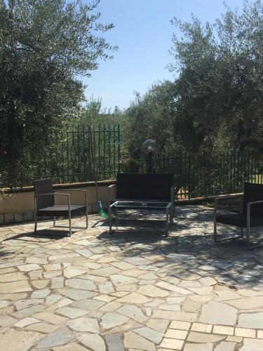 three chairs and a bench on a stone patio at L’Ulivo in Formia