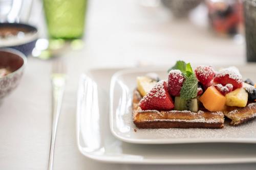 a plate of food with fruit on a table at Designhotel Gius La Residenza in Caldaro