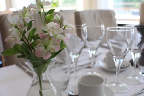 a vase of flowers on a table with wine glasses at Söråkers Herrgård in Söråker