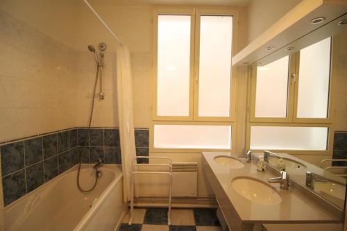 La salle de bains est pourvue de 2 lavabos, d'une baignoire et d'un miroir. dans l'établissement Vacances Perennes, à Cauterets