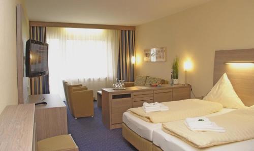 a hotel room with two beds and a desk at Hotel Bügener in Gronau