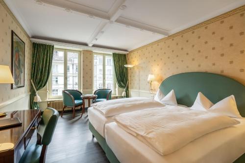 ein Hotelzimmer mit einem Bett, einem Tisch und Stühlen in der Unterkunft Boutique Hotel Belle Epoque in Bern