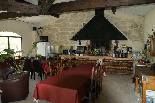un restaurant avec une table et des chaises et une cuisine dans l'établissement Chambre Foret du Mas des Fontaines, à Montagnac