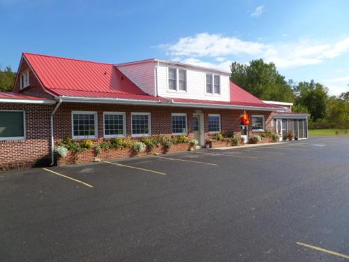 a building with a red roof and a parking lot at Lost River Motel in Lost City