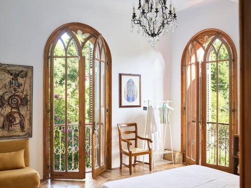 a room with two large windows and a chair and a chandelier at Le dimore de Il borgo del balsamico in Albinea