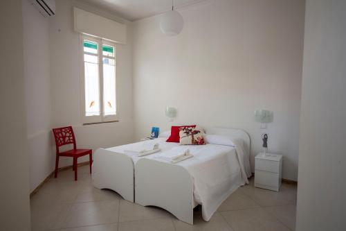 ein weißes Schlafzimmer mit einem Bett und einem roten Stuhl in der Unterkunft Il Galeone in Marina di Ragusa