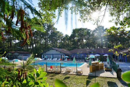 - une piscine avec des chaises et des parasols en face d'une maison dans l'établissement VVF Landes Moliets, à Moliets-et-Maa