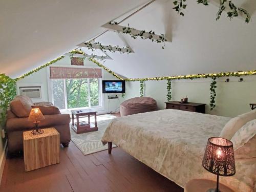 um quarto com uma cama, um sofá e uma televisão em Cute Cottage Above The Creek Farmhouse em Sylva