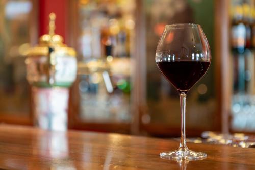 a glass of red wine sitting on a wooden table at Boutique Hotel Belle Epoque in Bern