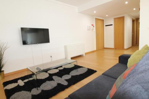 a living room with a couch and a tv on a wall at Parque das Nacoes River view ,free wifi in Lisbon