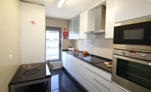a kitchen with white cabinets and a black counter top at Parque das Nacoes River view ,free wifi in Lisbon