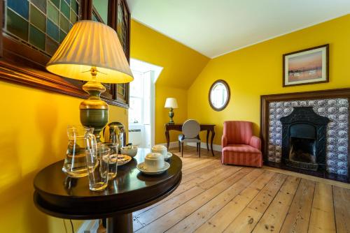 a living room with yellow walls and a table with a lamp at Torridon Estate B&B Rooms and Self catering Holiday Cottages in Torridon