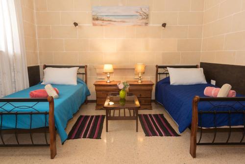 two beds in a room with two chairs and a table at Acomodation House Kavarna in Xagħra
