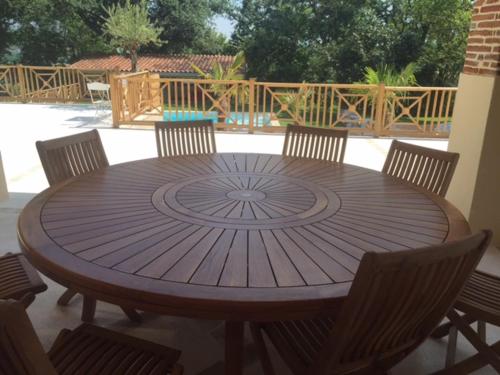 a wooden table with chairs around it on a patio at Guesthouse Le Pujol in Sainte-Foy-dʼAigrefeuille