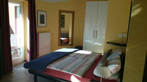 a bedroom with a bed and a mirror and a lamp at Ferienwohnung Sommerhus in Wiefelstede