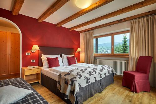 1 dormitorio con cama grande y pared roja en Garni Karin, en Corvara in Badia