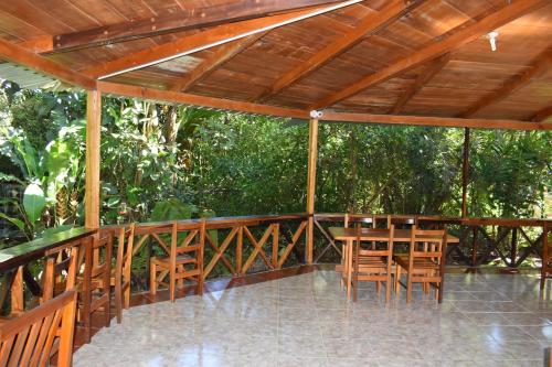 a wooden deck with chairs and a wooden ceiling at El Descanso in Mindo