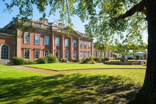 a large brick building with a tree in front of it at Colwick Hall Hotel in Nottingham