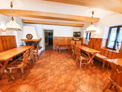 a dining room with wooden tables and chairs at Chalupa Barborka - Národní park Krkonoše, sauna, bazén, dětské hřiště, gril, 6 pokojů, kuchyň, společenská místnost s krbem in Vrchlabí