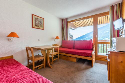 une chambre avec un canapé rouge, une table et une fenêtre dans l'établissement Quartier Crève Cœur - maeva Home, à Valmorel