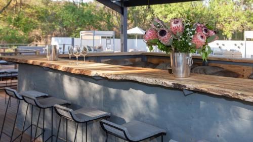 a wooden bar with chairs and a vase of flowers at Cradle Boutique Hotel in Lanseria