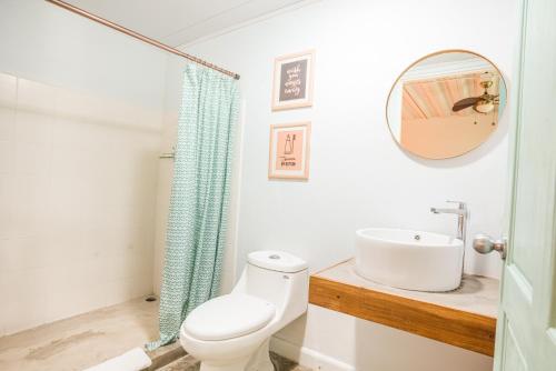 ein Badezimmer mit einem WC, einem Waschbecken und einem Spiegel in der Unterkunft Selina La Fortuna in Fortuna