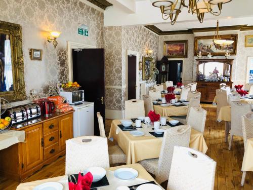 comedor con mesas y sillas y cocina en Castle Lodge Guest House 86-88 Sheil Rd L6 3AF, en Liverpool