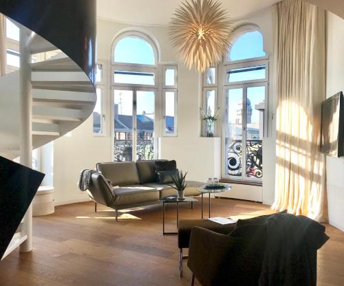 a living room with a couch and some windows at The Crown Penthouse Bahnhofstrasse in Zurich