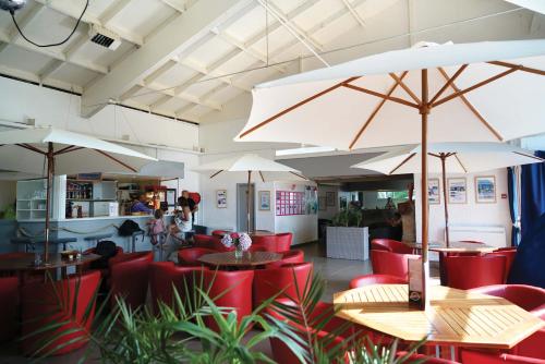 un restaurant avec des chaises rouges, des tables et des parasols dans l'établissement VVF Belle-Île-en-Mer, au Palais