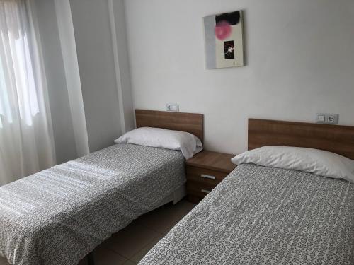 dos camas sentadas una al lado de la otra en un dormitorio en APARTAMENTOS ESJOVIAL, en Los Alcázares