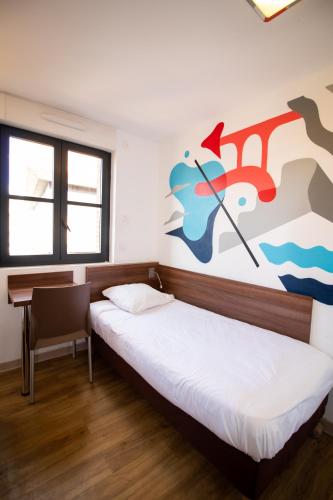 two beds in a room with a painting on the wall at Hôtel le Pastel in Toulouse