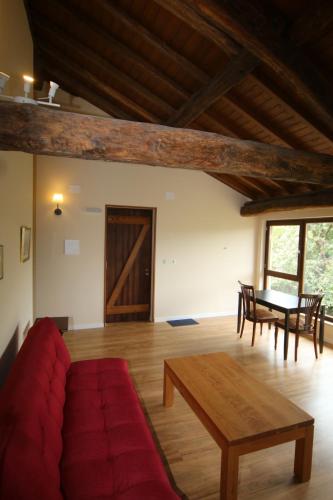 a living room with a red couch and a table at Pazo de Chaioso Ribeira Sacra in Maceda