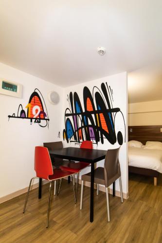a dining room with a table with chairs and surfboards on the wall at Hôtel le Pastel in Toulouse